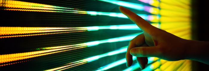 Close up of hand pointing to a screen with strips of colored light.