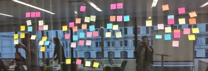 Photo of collaborative session with sticky notes on wall at workshop gathering.