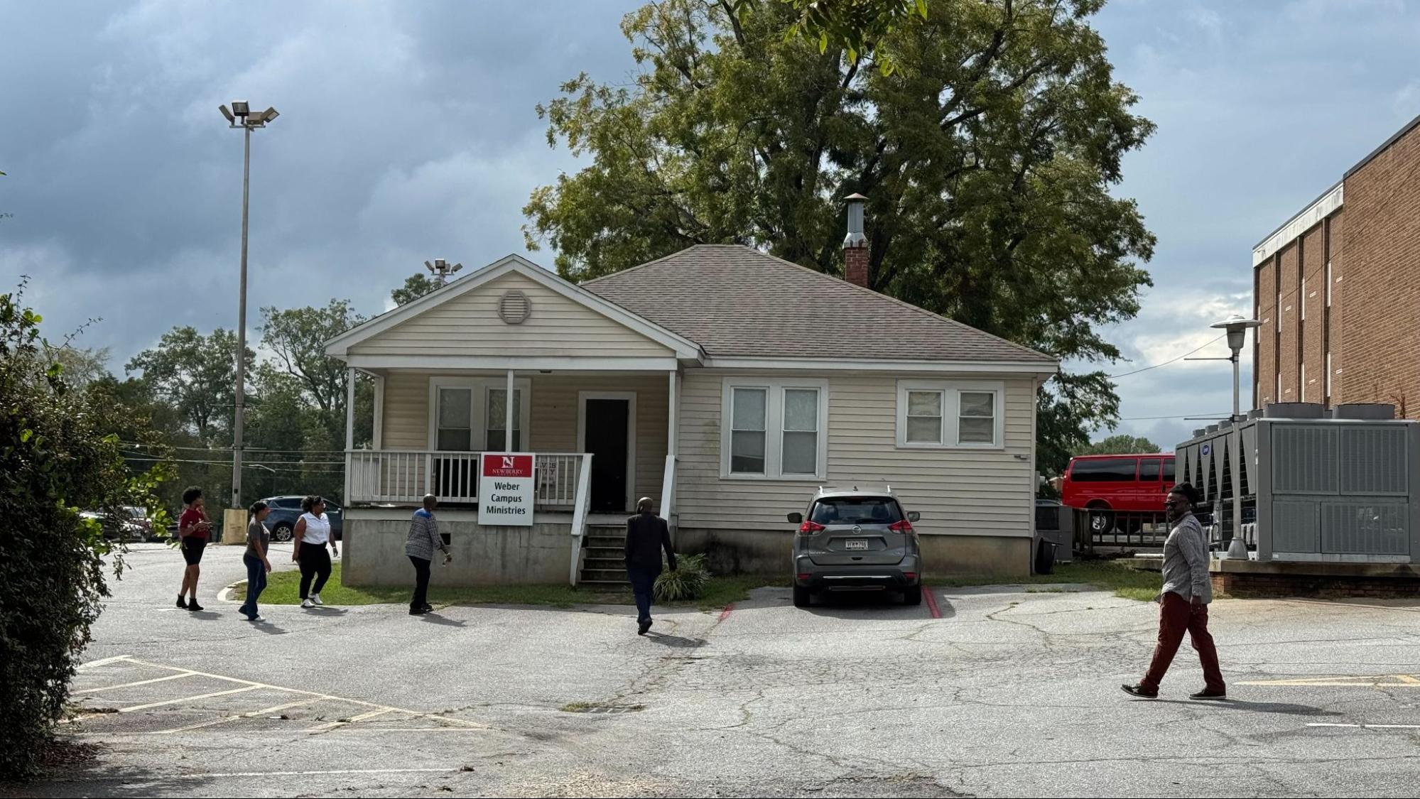 Small beige building labeled “Weber Campus Ministries” with people walking outside.