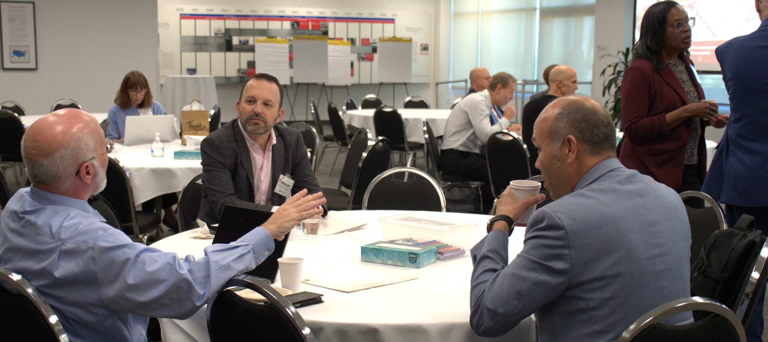 Three workshop participants in discussion at a round table.