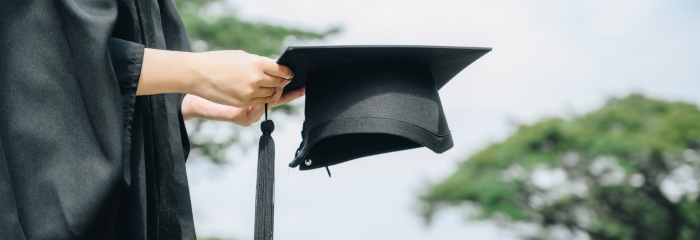 College graduate holding cap on graduation day.
